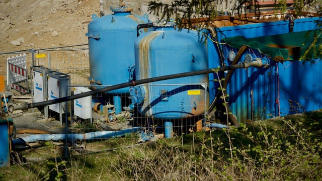 Outdoor industrial water filtration plant with large blue tanks under sunlight.