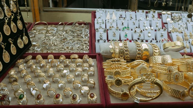 Showcase of elegant gold and silver jewelry in an Istanbul market's display case.