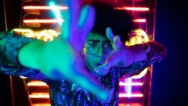 Dynamic portrait of a person surrounded by neon lights in a nightclub setting, expressing energy and style.
