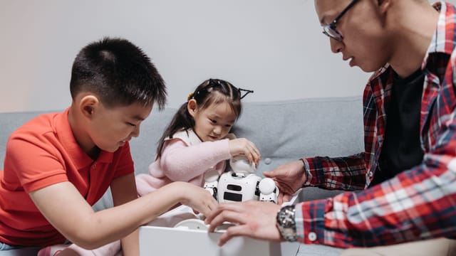A happy family unboxing a robot toy together indoors, highlighting joyful moments.