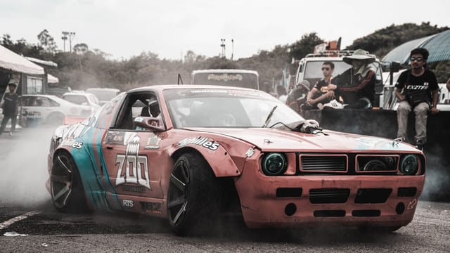 A drift car powers through a turn, creating a thrilling spectacle at a race event.