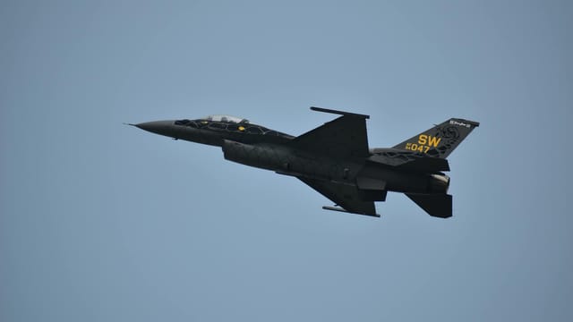 F-16 fighter aircraft soaring through the blue sky, showcasing aerodynamic design and military power.