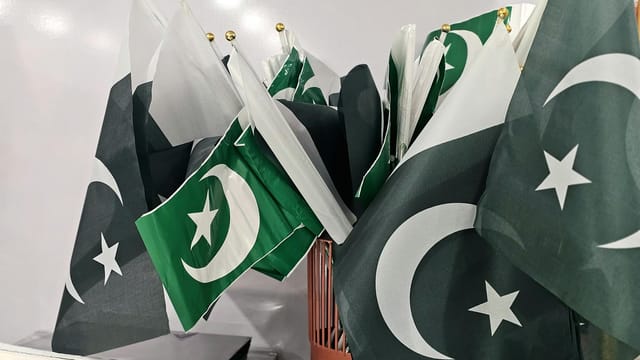 A variety of Pakistani flags grouped together indoors, emphasizing national pride.