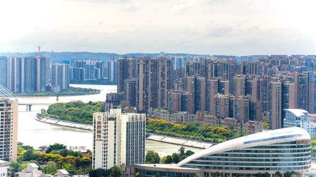 Aerial view of a modern cityscape with tall buildings and a winding river.