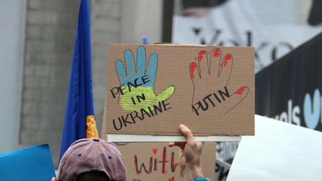 Crowd in Vancouver holding signs calling for peace in Ukraine during a protest.