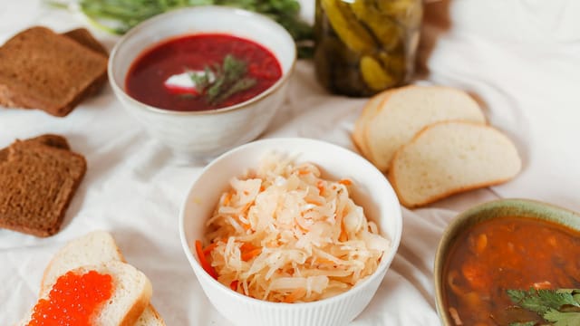 A diverse spread featuring Russian foods like borscht, sauerkraut, and caviar on a table.