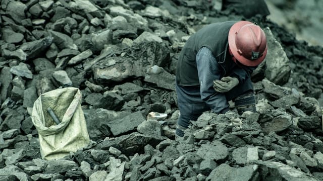 A woman mining for gold in La Rinconada, Peru, surrounded by rocks and debris.