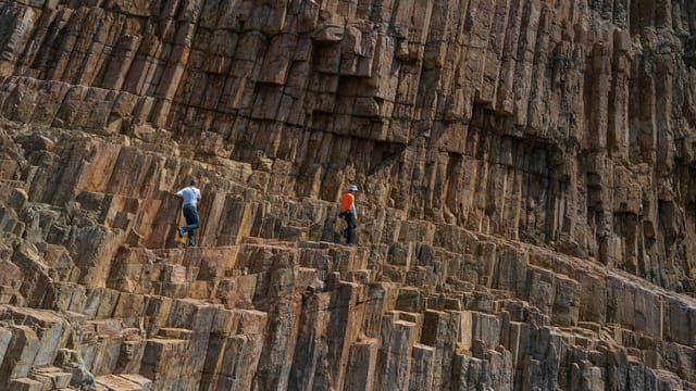 Adventurers scaling unique volcanic rock formations outdoors.