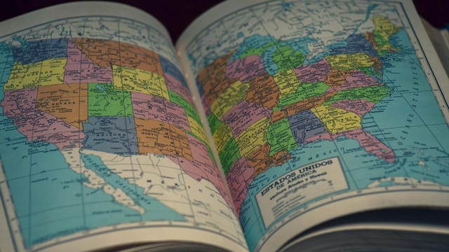 Open atlas showing a colorful map of the United States, highlighting states with vibrant colors.
