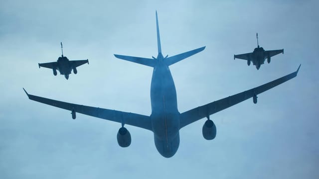 Dynamic silhouette of fighter jets flying in strategic formation in a clear blue sky.