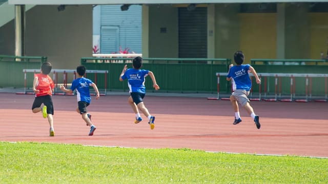 Boys running on a track during a sunny day in New Territories, Hong Kong.