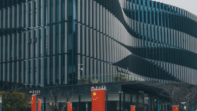 Contemporary architectural building with Chinese flags displayed prominently.