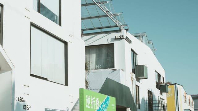 Contemporary white concrete building with glass windows and minimalist design under a clear blue sky.