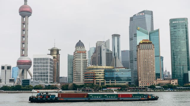 Panoramic view of Shanghai skyscrapers and a cargo boat on Huangpu River, capturing the city's modern architecture.