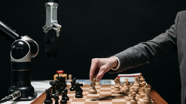 A robotic arm plays chess against a human, symbolizing AI innovation and strategy.