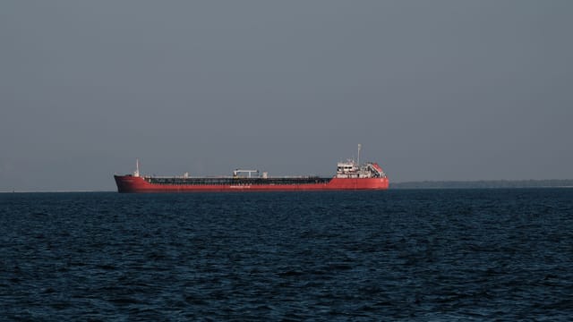 A large red cargo ship sailing on the calm waters of the Aegean Sea near İzmir, Türkiye.