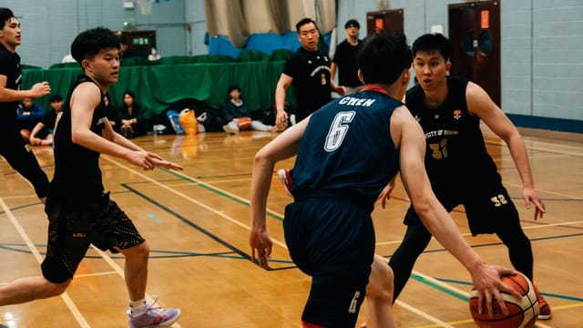Energetic scene of a competitive indoor basketball game with players in action.