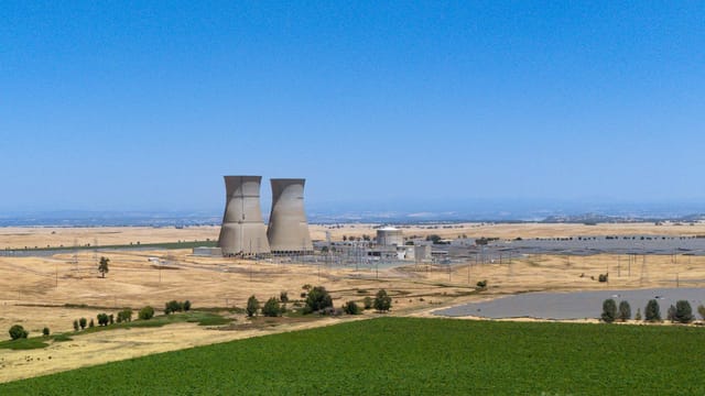Aerial view of a nuclear power plant surrounded by greenery in California under a clear blue sky.