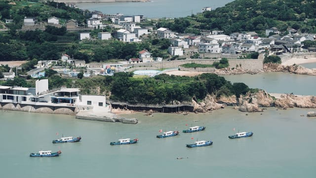 Scenic coastal village view with fishing boats in a serene bay.