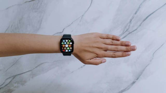 Overhead view of a smartwatch on an arm against a marble background representing modern technology.