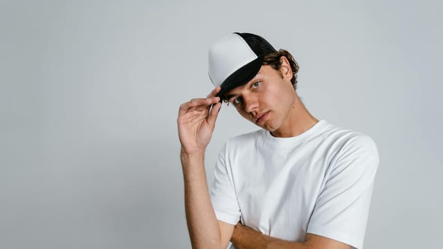 Young man wearing a cap and white t-shirt against a plain background.