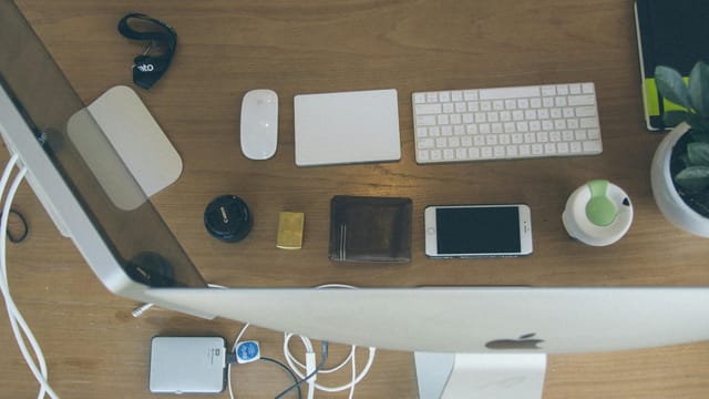 Top-down view of an organized modern desk setup featuring Apple devices and accessories.