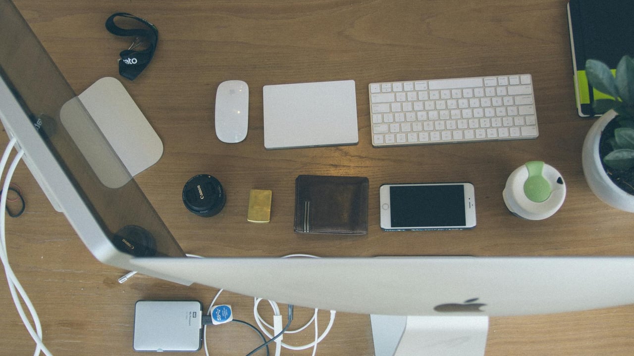 Top-down view of an organized modern desk setup featuring Apple devices and accessories.