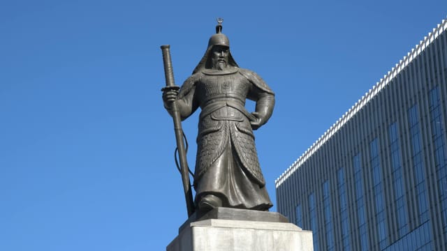 The iconic statue of Admiral Yi Sun-sin stands prominently in Seoul under a clear blue sky.