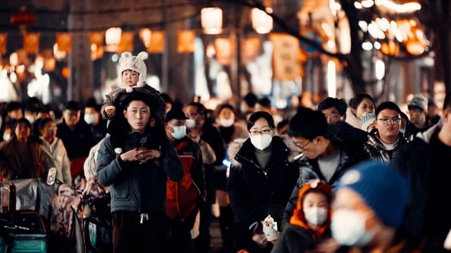 Mask-wearing crowd on a festival street in Weifang, China, capturing the bustling atmosphere.