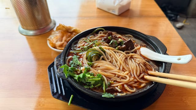 Delicious hot noodle soup with beef, cilantro, and spices served on a wooden table.