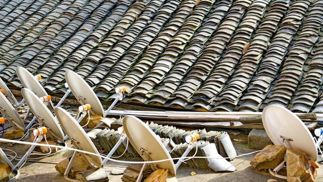 A row of satellite dishes set against an intricately tiled roof, depicting modern technology blending with traditional architecture.