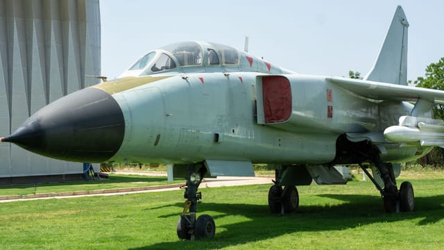 A historic military fighter jet displayed outside on a sunny day, perfect for aviation enthusiasts.
