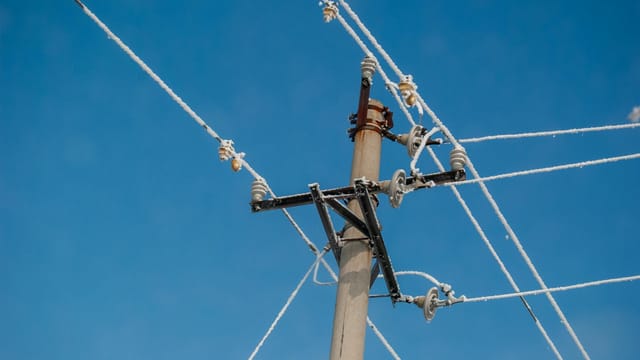 Frost-covered utility pole wires under a clear blue sky in Harbin, winter scene.