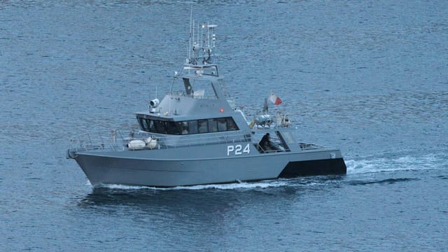 Military patrol boat cruising through ocean waters.
