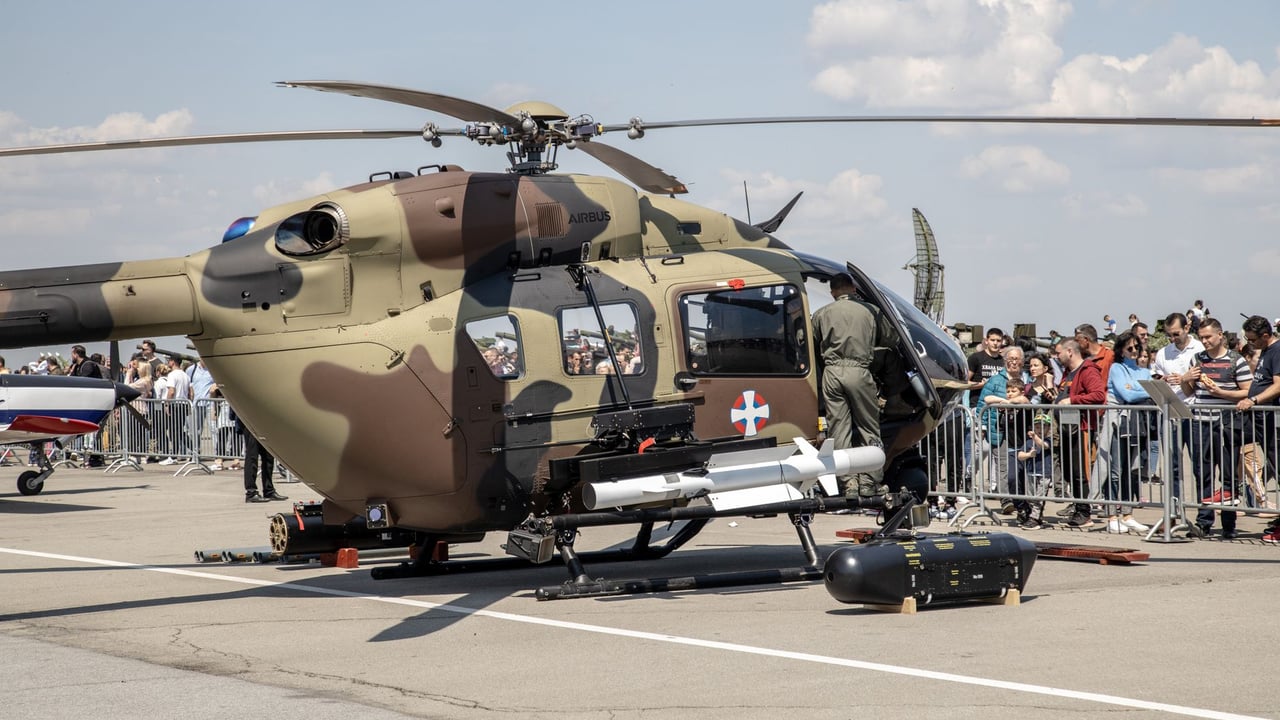 Army helicopter showcased at airshow with crowd in attendance on a sunny day.
