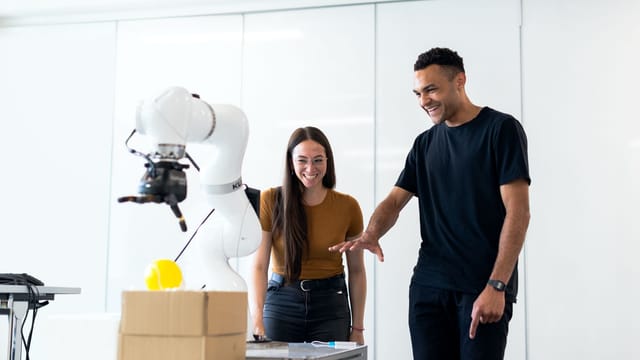 Two engineers collaborating on testing a futuristic robotic prototype in a modern indoor lab.