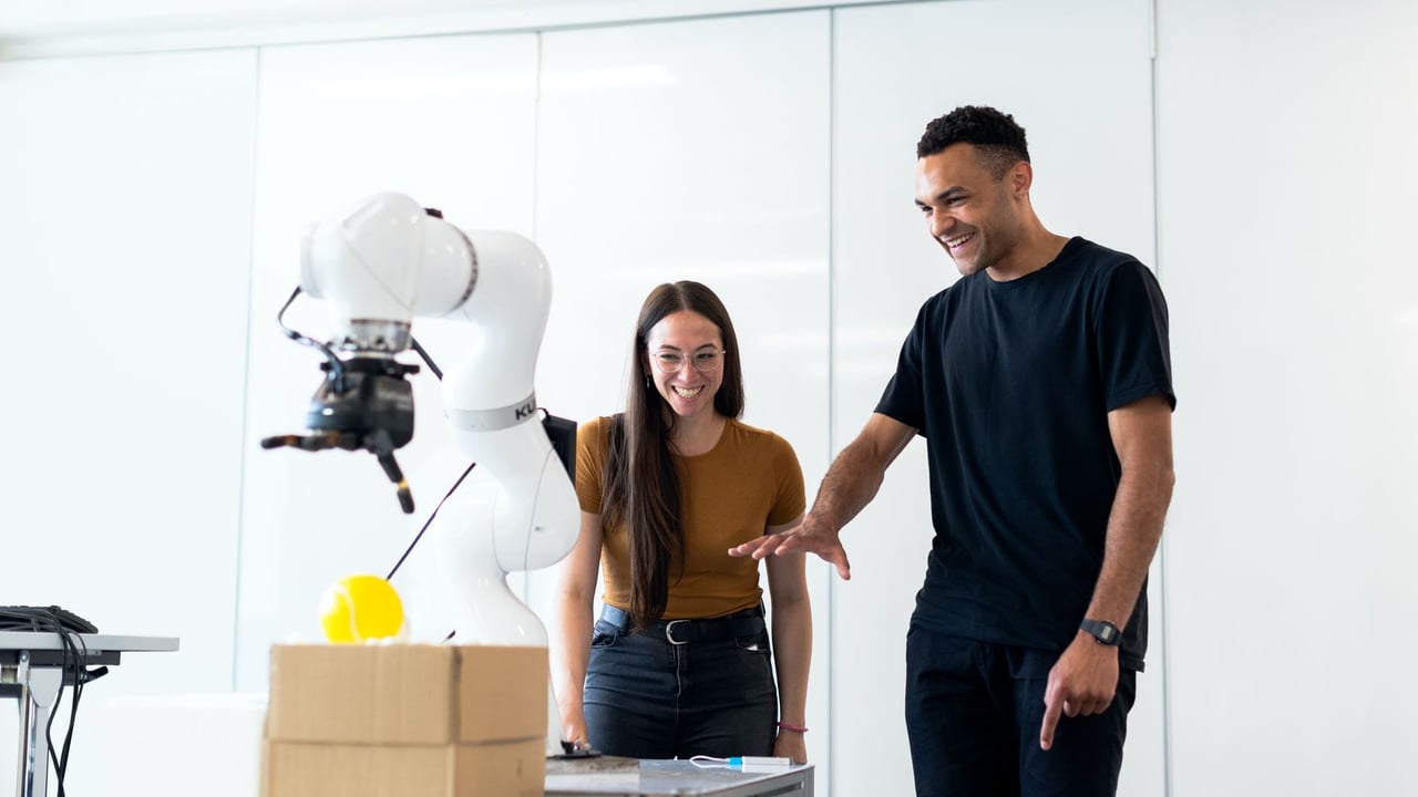 Two engineers collaborating on testing a futuristic robotic prototype in a modern indoor lab.