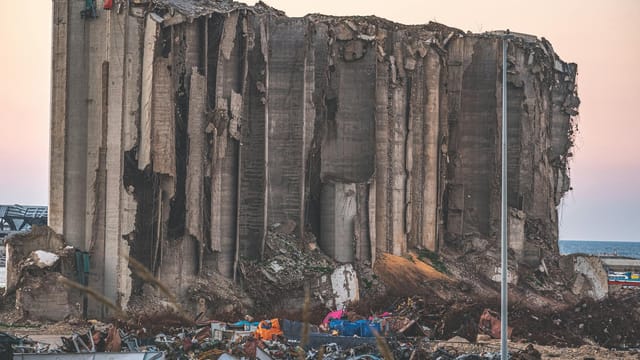 A large concrete structure lies in ruins, symbolizing the destruction in Beirut, Lebanon.