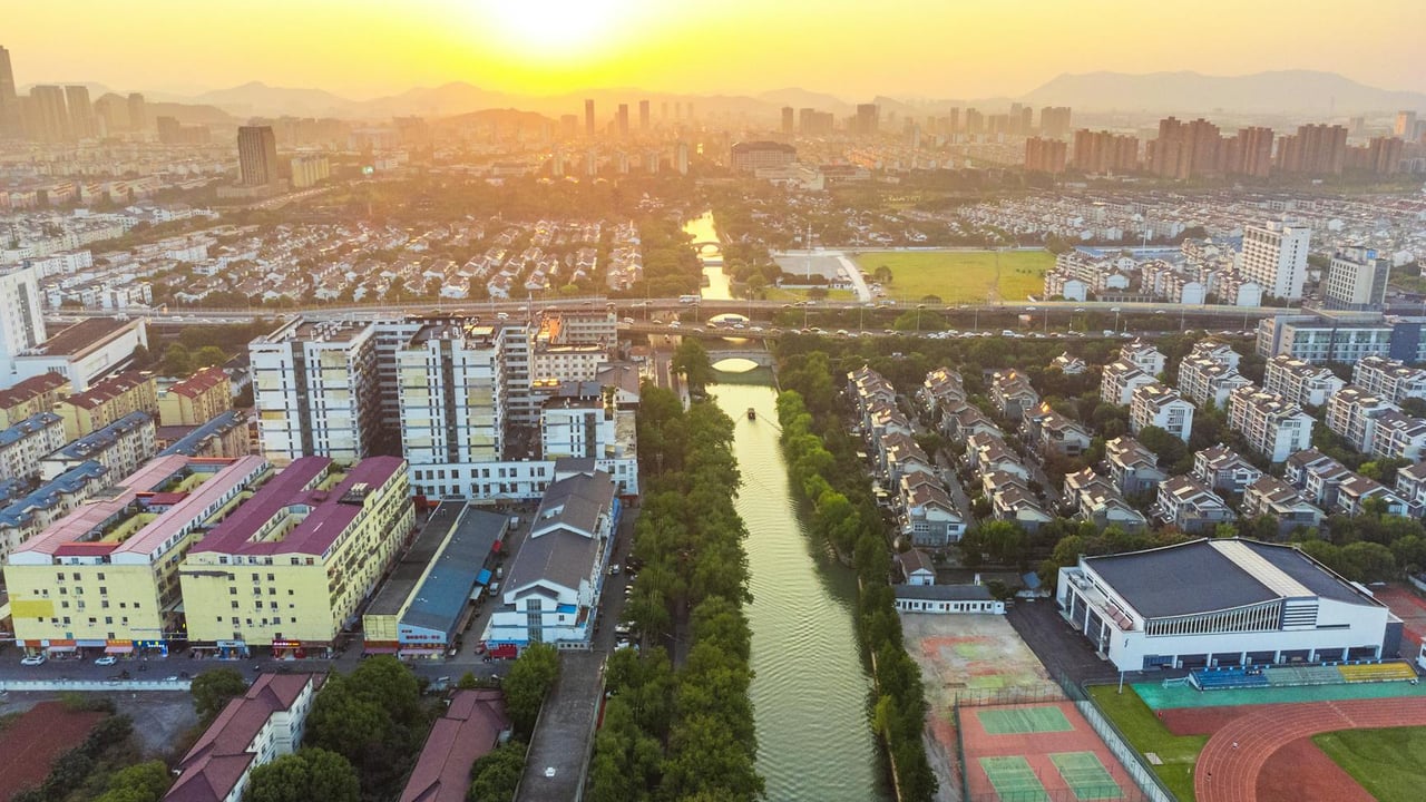 Stunning aerial cityscape of Suzhou, China at sunset with vibrant skyline and waterway.