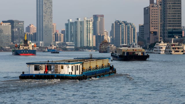 Barges navigate the Huangpu River against the stunning backdrop of Shanghai's modern skyscrapers.