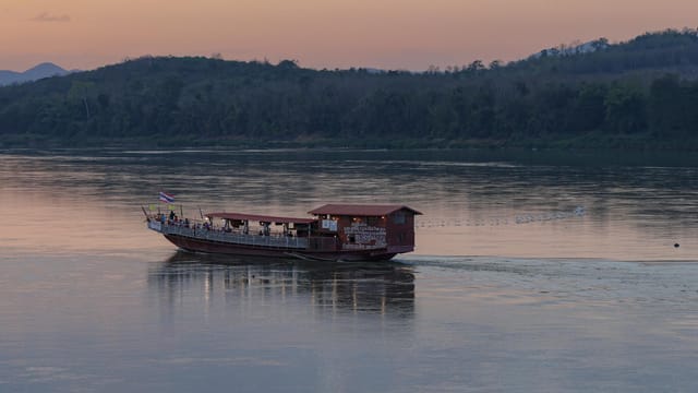 A tranquil evening view of a boat on the Mekong River at sunset in Chiang Khan, Thailand.