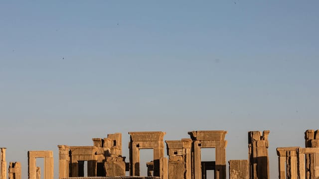 Explore the majestic Apadana ruins of Persepolis under a clear blue sky, showcasing Persian architecture.