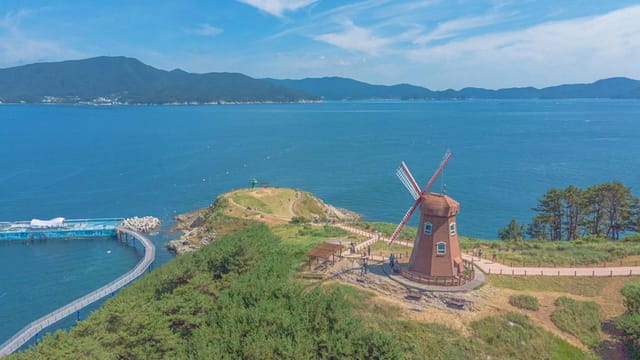 Aerial shot of Windy Hill's windmill overlooking the serene ocean in Geoje-si, South Korea.