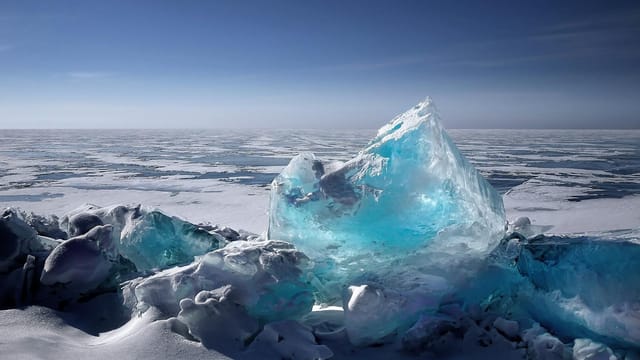 Captivating ice formation on a frozen lake under a bright blue sky during winter.