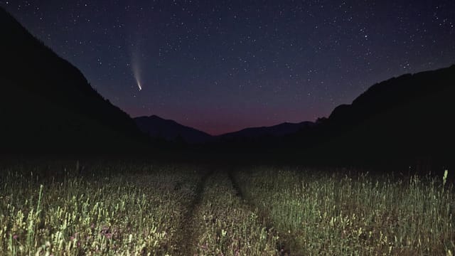 Stunning night landscape of a shooting star and field under a starry sky. Perfect for nature lovers.
