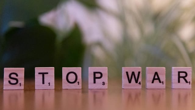 Wooden letter tiles spelling 'Stop War' symbolizing peace and anti-war activism.