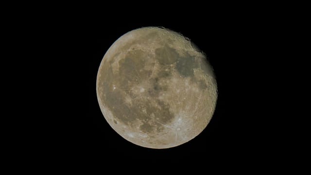 A detailed view of the full moon in a clear night sky, showcasing its surface features.