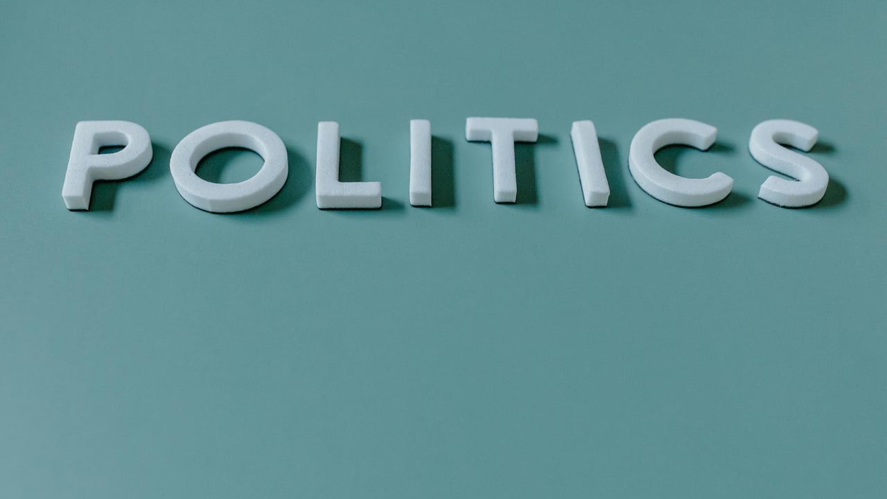 Close-up image of the word 'Politics' against a teal green background, highlighting political themes.