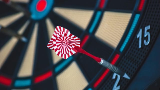 A dart striking the bullseye on a dartboard, showcasing precision and accuracy.