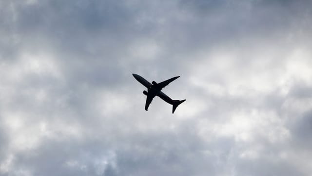 Silhouette of an airplane flying through a cloudy sky, capturing a serene and powerful aviation moment.